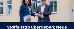 Gerd Heimbach (rechts) übergibt Siiri Drechsel (links) seinen Büroschlüssel vor dem Verwaltungsgebäude.